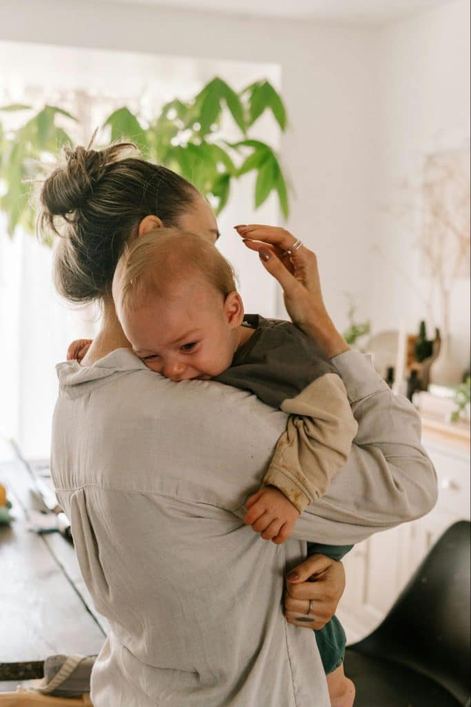 Caregiver holding a baby at home during an ordinary moment of care