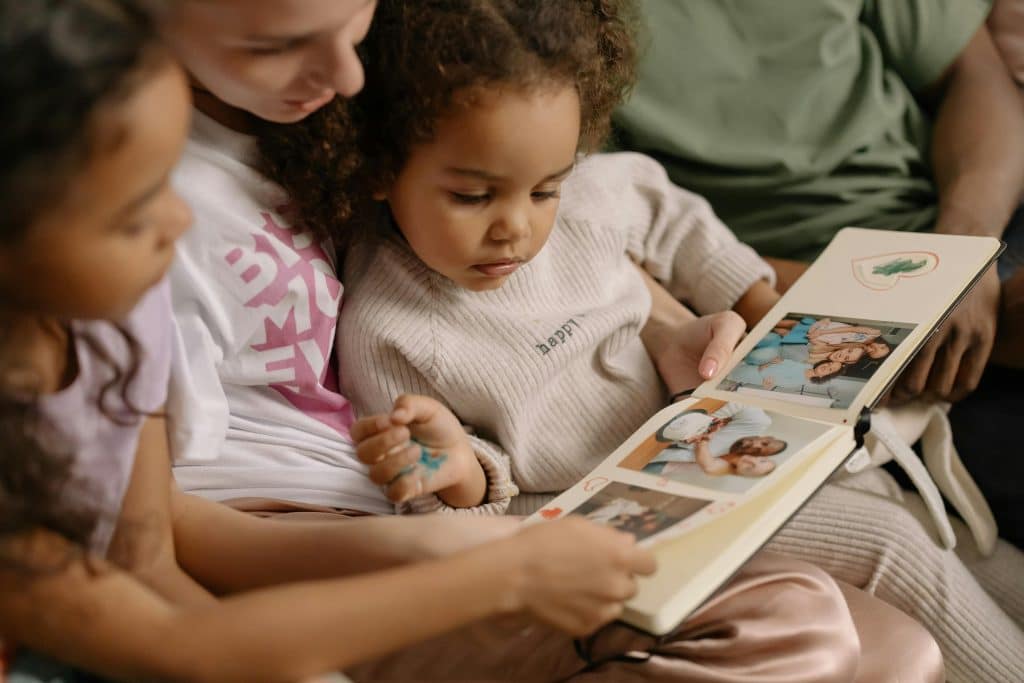 Children sitting together looking through a family photo album during a quiet moment at home