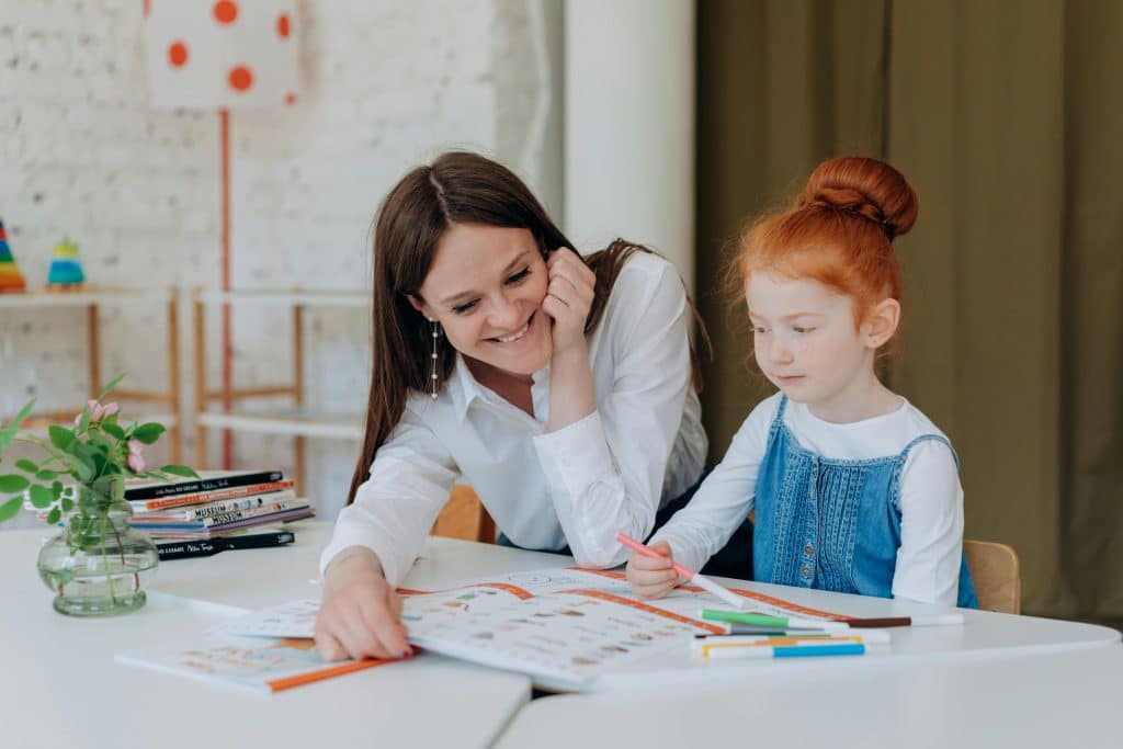 A caregiver and child sharing a peaceful moment, drawing together at a table, highlighting the nurturing connection in long term childcare