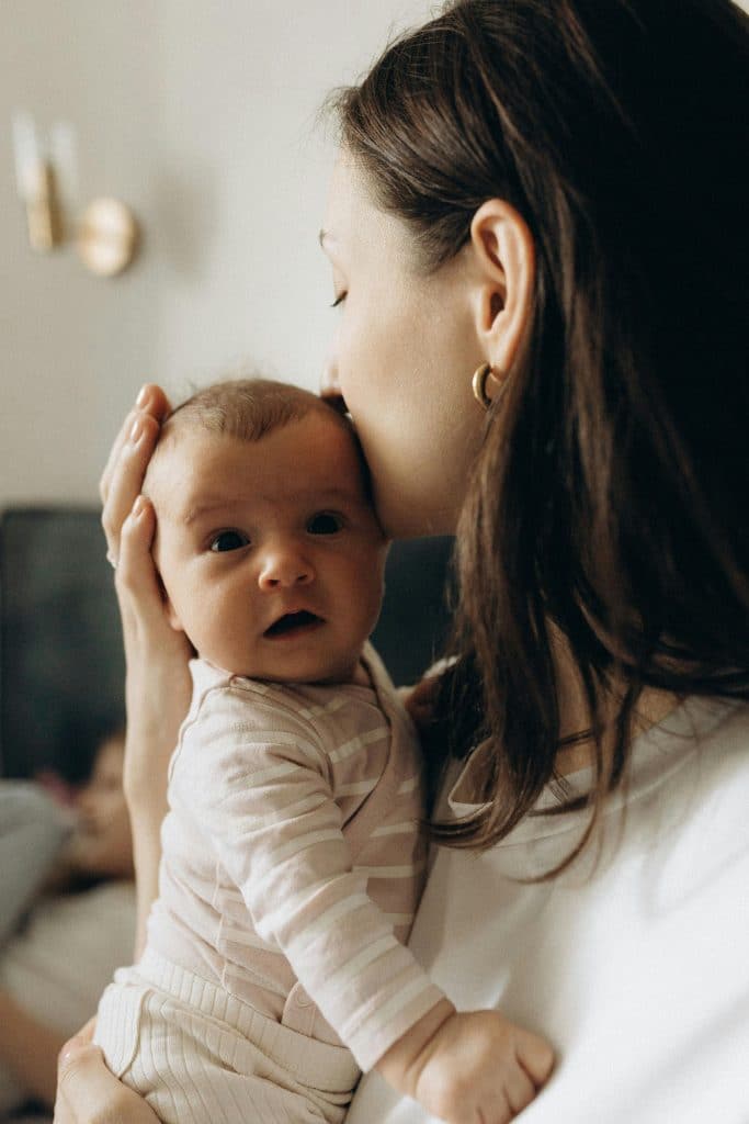 Mother holding a baby close at home, representing emotional presence, intimacy, and the quiet foundation that makes connection possible