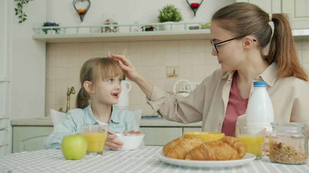 Caregiver and young child sharing a calm breakfast together at the kitchen table before the workday begins