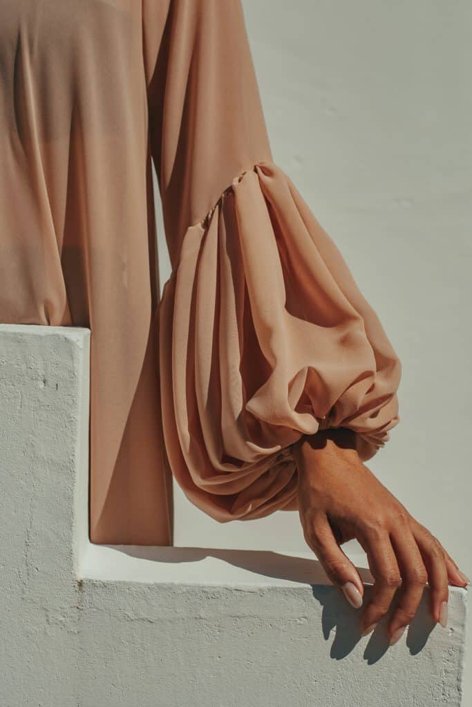 Close up of a woman’s hand and soft fabric, representing care, support, and human centered approaches to women’s health