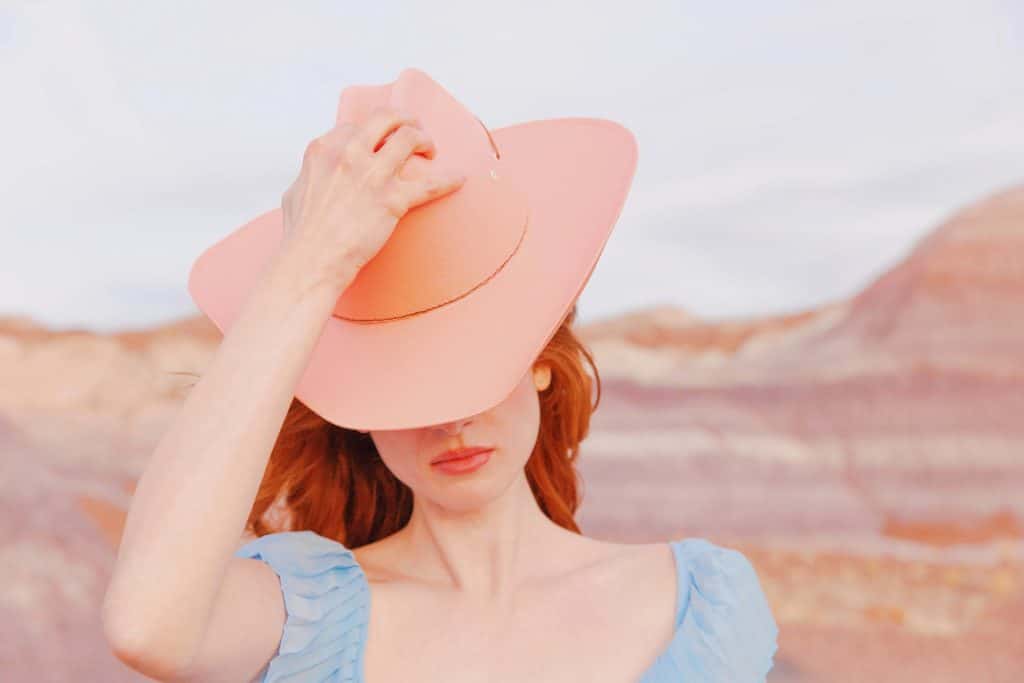 Woman wearing a wide brim hat partially covering her face, symbolizing quiet awareness, avoidance, and the hidden nature of women’s health concerns