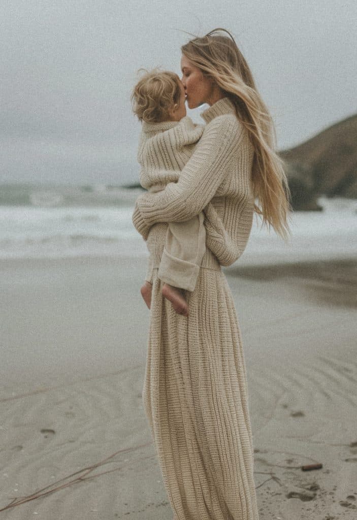 mother kissing child on beach